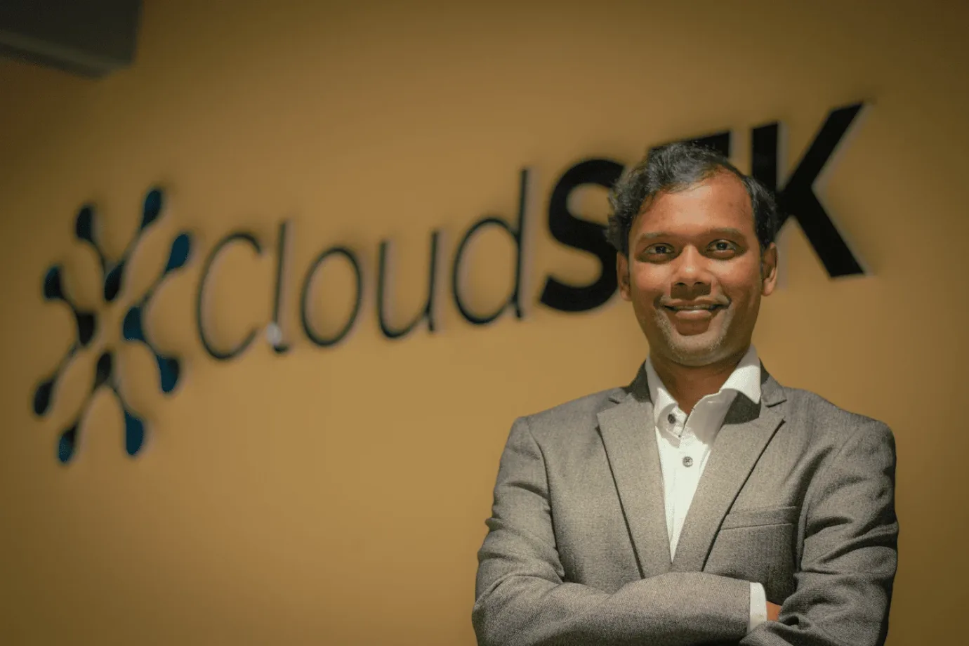 A member of the CloudSEK team in front of the CloudSEK office sign
